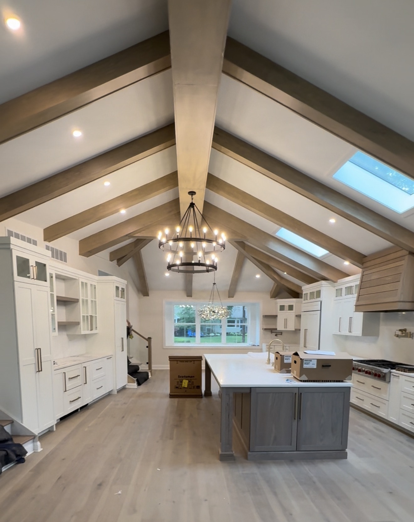 Custom kitchen with exposed ceiling beams and elegant chandelier